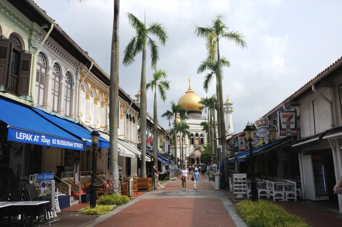 Bussorah Street in Kampong Glam, Singapore, with shophouses, palm trees and the golden dome of Masjid Sultan