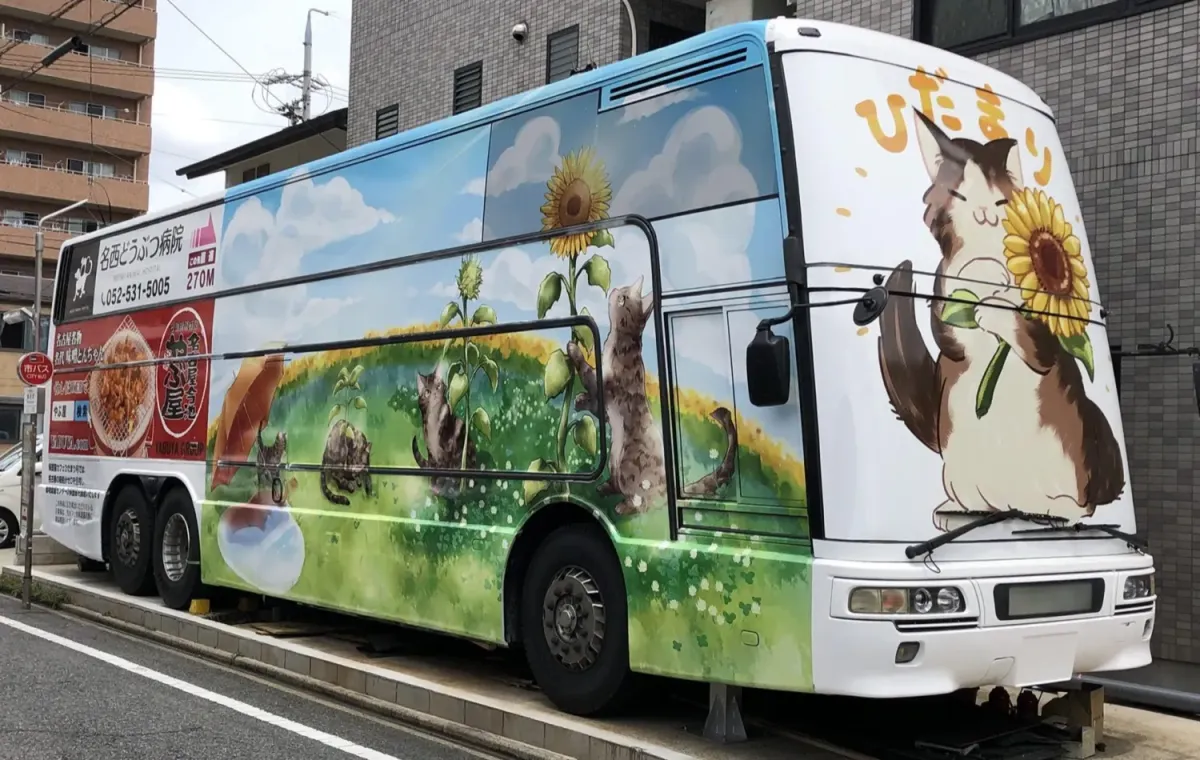 名古屋の路上に停まる、猫とひまわりが描かれた2階建てバスのひだまり号